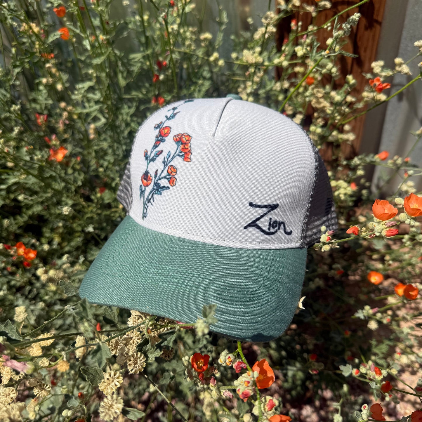 Trucker hat with floral design and Zion test  in front of a globemallow background